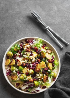 Lahana, kinoa, fındık ve kızılcık ile kaplı koyu bir arka planda peçeteyle kavrulmuş brussel salatası. Sağlıklı beslenme konsepti. Üst görünüm ve kopyalama alanı.