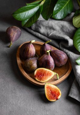 Yapraklar ve peçeteyle birlikte siyah arka planda, ahşap bir tabakta sulu incir. Kırsal tarzda sağlıklı ve lezzetli meyve kavramı. en üstteki görünüm ve kopyala.