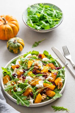 Balkabağı, roka, peynir, fındık ve kuru meyveli sonbahar salatası. Sağlıklı beslenme konsepti. Vejetaryen menüsü. Üst görünüm.