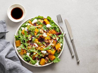 Sonbahar salatası, balkabağı, roka, peynir, fındık ve kuru meyveli soya soslu. Sağlıklı beslenme konsepti. Vejetaryen menüsü. Üst görünüm ve kopyalama alanı.