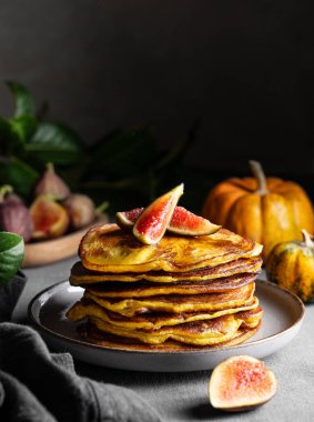 Balkabağı ve ballı gözleme ve taze meyve ve sebzelerle dolu karanlık bir arka planda incir. Ev yapımı sıcacık sonbahar yemekleri kırsal tarzda. Ön görünüm ve boşluk kopyala.