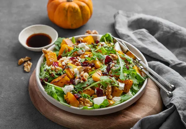 Balkabaklı salata, roka peyniri, fındık ve kurutulmuş böğürtlen soya soslu, tahta tahtada. Kırsal tarzda sağlıklı beslenme konsepti. Vejetaryen menüsü. 