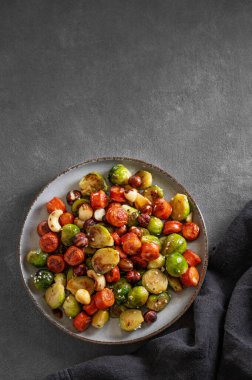 Sosisli, fındıklı ve susamlı filizler. Koyu arkaplanda, peçeteli bir tabakta besleyici bir yemek düşünün. Üst görünüm ve kopyalama alanı.