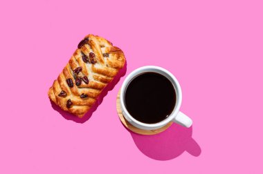 Kahve fincanı ve pembe arka planda gölgeli taze pekan fındıklı çörek. Yaratıcı düzen ve sağlıklı kahvaltı konsepti. Üst görünüm ve kopyalama alanı.