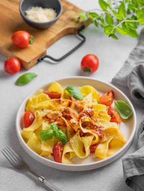 Domates soslu, fesleğenli ve parmesan peynirli ev yapımı tagliatelle makarnası, tahta bir tabakta taze otlarla birlikte. Geleneksel İtalyan yemeği kavramı. 
