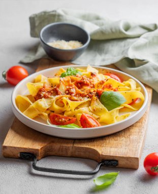 Domates soslu Tagliatelle makarnası, fesleğen ve parmesan peyniri ahşap bir tabakta yakın plan üzerinde. Geleneksel ev yapımı İtalyan yemeği kavramı. 