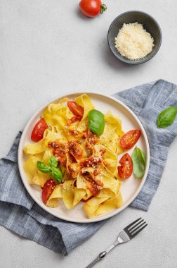 Düz bir tabakta domates soslu, fesleğenli ve parmesanlı makarna. Geleneksel ev yapımı İtalyan yemeği kavramı. Üst görünüm ve kopyalama alanı.