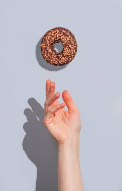 Mavi arka planda gölgeli uçan jöleli çikolatalı çörek. Yaratıcı bir model ya da hızlı kahvaltı reklamı konsepti. Ön görünüm ve boşluk kopyala.