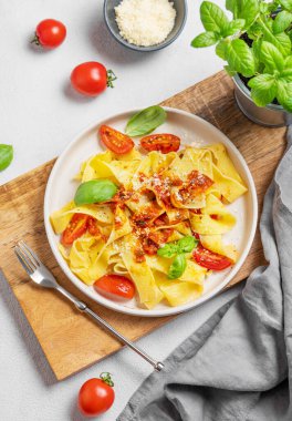 Domates soslu Tagliatelle makarnası, fesleğen ve parmesan peyniri taze otlarla birlikte tahta bir tabakta. Geleneksel ev yapımı İtalyan yemeği kavramı. Üst görünüm