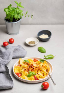 Ev yapımı tagliatelle ya da domates soslu pappardelle makarna, fesleğen ve parmesan peyniri bir tabakta peçete ve bitkiyle birlikte. Geleneksel İtalyan yemeği konsepti. 