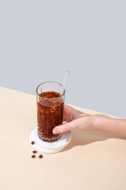 Buzlu soğuk kahve bardağı ve kahve çekirdekleri ve gölgeli sarı ve mavi arka planda saman. Yaz ferahlatıcı modern içki. Üst görünüm ve kopyalama alanı.