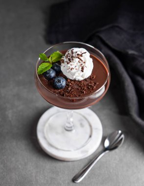 Krem şantili çikolatalı puding, taze yaban mersini ve siyah arka planda kaşık ve peçeteli nane şekeri. Kremalı tatlı ya da panna cotta 'nın modaya uygun sunumu kavramı. Üst görünüm.