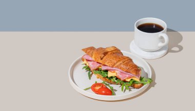 Jambonlu, peynirli, domatesli ve roka arkaplanlı kruvasan sandviçi ve bir fincan espresso kahvesi. Sağlıklı bir kahvaltı ya da brunch kafe menüsü. Üst görünüm ve kopyalama alanı.