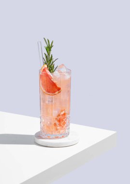 Üzümlü, biberiyeli ve buzlu, mavi arka planda gölgeli bir bardakta taze bir kokteyl. Yaz turunçgil içeceği ya da kafe reklamları için limonata konsepti. Ön görünüm ve boşluk kopyala.