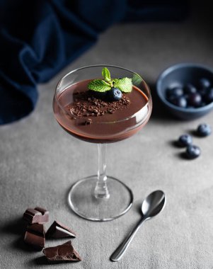 Naneli ve taze yaban mersinli uzun bir bardakta çikolatalı puding çikolata parçaları, böğürtlen ve peçeteli. Ev yapımı kremalı tatlı veya panna cotta konsepti.