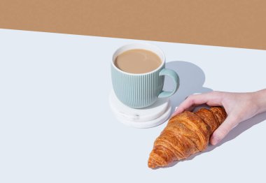 Beyaz arka planda taze kruvasan ve sütlü bir fincan kahve. Kafe reklamları ya da Fransız kahvaltı konsepti için yaratıcı bir model. Üst görünüm ve kopyalama alanı.