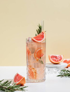Sarı arka planda greyfurt, biberiye ve buzlu taze bir kokteyl. Yaz turunçgil içeceği ya da kafe reklamları için limonata konsepti. Ön görünüm ve boşluk kopyala.