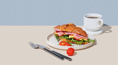 Jambonlu, peynirli, domatesli ve roka arkaplanlı kruvasan sandviçi ve bir fincan taze kahve. Sağlıklı bir kahvaltı ya da brunch kafe menüsü. Boşluğu kopyala