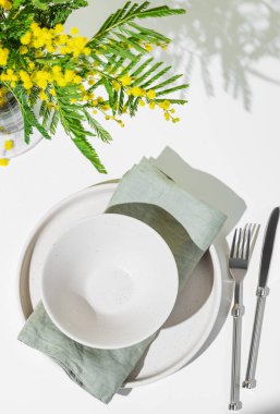 Kadınlar günü, düğün ya da anneler günü için açık arkaplanda sarı mimoza çiçekleri olan bahar kutlaması için sofra kurulumu. Restoran menüsü konsepti. Üst görünüm ve kopyalama alanı.