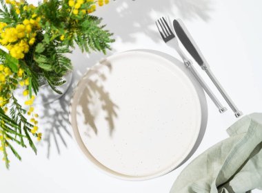 Kadınlar günü, düğün ya da anneler günü için açık arkaplanda sarı mimoza çiçekleri olan bahar kutlaması için sofra kurulumu. Restoran menüsü konsepti. Üst görünüm ve kopyalama alanı.