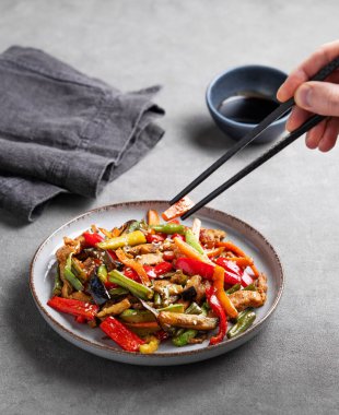 Elleri yemek çubukları, kızarmış sebzeler ve soya soslu ve peçeteli et. Susamlı Asya fast-food kavramı. Boşluğu kopyala.