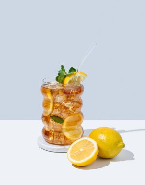 Limonlu buzlu buzlu çay ve beyaz ve mavi arka planda gölgeli bir bardak nane şekeri. Ferahlatıcı içecek ya da limonata, menü reklam modeli. Ön görünüm ve boşluk kopyala.