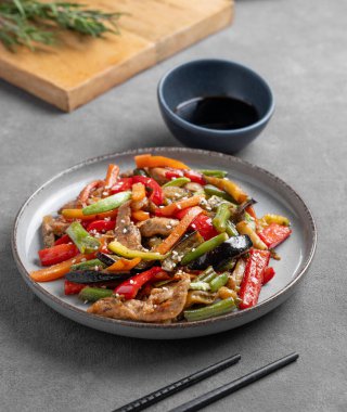 Sebzeli kızartma ve koyu arkaplanda et, yemek çubukları, bir bardak su ve soya sosu. Susamlı Asya fast-food konsepti. 