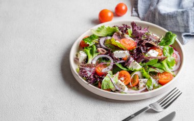 Hafif arkaplanda kiraz domatesli sebze salatası (Yunan salatası), feta peyniri, marul, zeytin ve kırmızı soğan. Sağlıklı beslenme konsepti. Boşluğu kopyala.