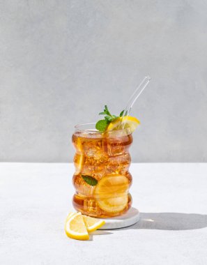 Limonlu buzlu buzlu çay ve arka planda gölgeli hafif desenli bir bardakta nane şekeri. Ferahlatıcı içecek ya da limonata modası. Ön görünüm ve boşluk kopyala.