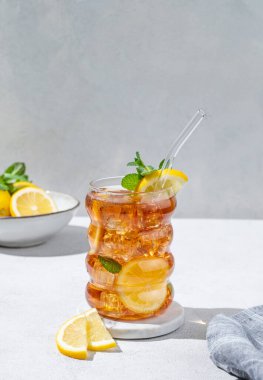 Limonlu buzlu buzlu buzlu çay ve narenciye arkaplanlı hafif desenli bir bardakta nane. Ferahlatıcı içecek ya da limonata modası. Ön görünüm ve boşluk kopyala.