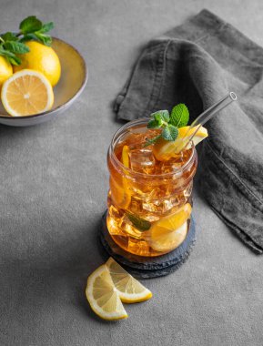 Limonlu buzlu buzlu çay ve nane şekeri gark grisi arka planda narenciye ve peçeteyle birlikte. Ferahlatıcı içecek ya da limonata modası. Üst görünüm ve kopyalama alanı.