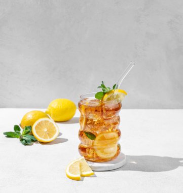 Limonlu buzlu buzlu buzlu çay ve hafif arka planda bir bardak nane şekeri. Gölge ve narenciye meyveleriyle birlikte. Ferahlatıcı bir kokteyl ya da limonata konsepti. Ön görünüm ve boşluk kopyala.