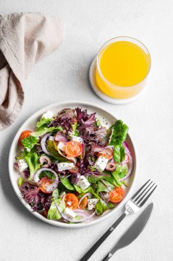 Sebze salatası (Yunan salatası) domates, peynir, marul, zeytin ve soğanlı hafif arkaplanda bir bardak meyve suyu ile birlikte. Sağlıklı beslenme konsepti. Üst görünüm ve kopyalama alanı.