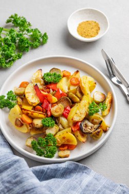 Pişmiş sebze, patates, lahana, biber ve soğan taze maydanozlu hafif bir arka planda. Vejetaryen diyet yemeği konsepti. Üst görünüm