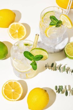 Mocktail mojito 'yu limon, limon, nane ve buzla tazeliyorum. Hafif bir arka planda meyveli limonata. Yaz modasına uygun soğuk içecek konsepti. Üst görünüm.