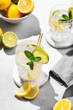 İki bardak mojito kokteyli. Taze limon, limon, nane ve buzlu. Arka planda güneş ışığı ve gölge var. Modaya uygun bir yaz tatili konsepti limonlu moktail içeceği. Üst görünüm.