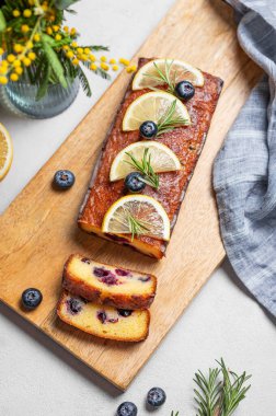 Şeker jöleli limonlu turta, biberiye ve narenciye dilimleri ile süslenmiş yaban mersini, açık arkaplanda tahta bir tahta üzerinde. Lezzetli ev yapımı meyve ve böğürtlenli pişirme kavramı. Üst görünüm.