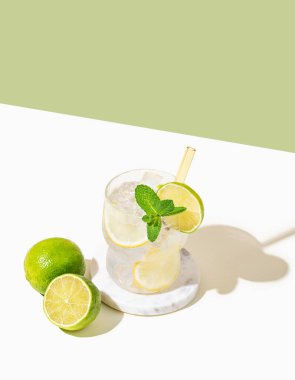 Limonlu, limonlu, naneli ve buzlu mojito. Beyaz yeşil arka planda limonata. Bar menüsü reklamları veya afişler için yaz modasına uygun içecek konsepti. Boşluğu kopyala.