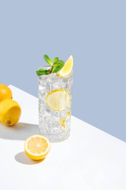 Limonata, nane ve buzlu beyaz mavi arka planda gölgeli ve meyveli bir bardak. Yaz turunçgil içeceği ya da kafe reklamları için mojito kokteyli konsepti. Boşluğu kopyala.