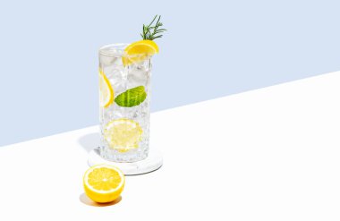Limonlu limonata, biberiye ve beyaz mavi arka planda buzlu bir bardak. Yaz turunçgil içeceği ya da kafe reklamları için mojito kokteyli konsepti. Boşluğu kopyala.