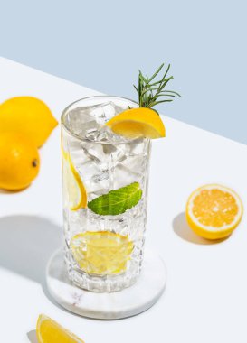 Limonlu mojito kokteyli, biberiye ve buzlu beyaz mavi arka planda meyveli bir bardak. Yaz turunçgil içeceği ya da kafe reklamları için limonata konsepti. 
