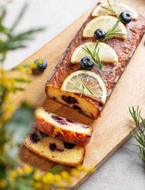 Şeker jöleli limonlu turta, biberiye ve narenciye dilimleri ile süslenmiş yaban mersini, açık arkaplanda tahta bir tahta üzerinde. Lezzetli ev yapımı meyve ve böğürtlenli pişirme kavramı. Üst görünüm.