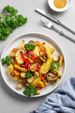 Pişmiş sebze, patates, lahana, biber ve soğan taze maydanozlu hafif bir arka planda. Vejetaryen diyet yemeği konsepti. Üst görünüm.