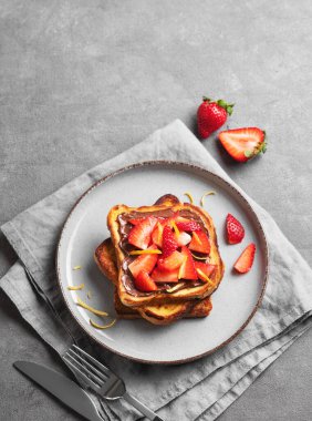 Koyu bir zemin üzerinde çikolata kremalı ve çilekli kızarmış ekmek taze böğürtlen ve peçeteyle birlikte. Lezzetli ve besleyici ev yapımı kahvaltı kavramı. Üst görünüm, alanı kopyala.