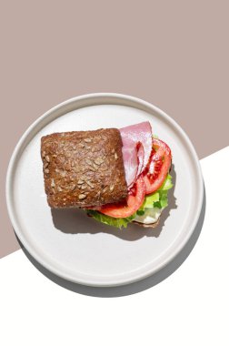 Prosciutto, domates, marul ve sostan yapılmış kahverengi sarı arka planda gölgeli tahıllı sandviç. Kafe reklamları veya afişler için sağlıklı kahvaltı konsepti. Üst görünüm.