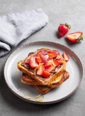 Koyu bir zemin üzerinde çikolata kremalı ve çilekli kızarmış ekmek ve taze böğürtlen. Lezzetli ve besleyici ev yapımı kahvaltı kavramı. 
