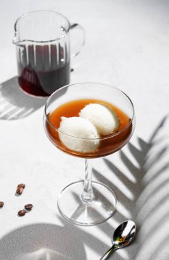 Afogato kahvesi, vanilyalı dondurma kepçesi ve espresso, kahve çekirdekleri ve palmiye yaprağı gölgesiyle beyaz arka planda uzun bir bardakta. Cafe menüsü reklamları için klasik İtalyan tatlı konsepti. 