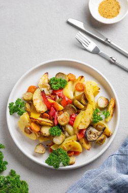 Pişmiş sebze, patates, lahana, biber ve soğan taze maydanozlu hafif bir arka planda. Vejetaryen diyet yemeği konsepti. Üst görünüm ve kopyalama alanı.