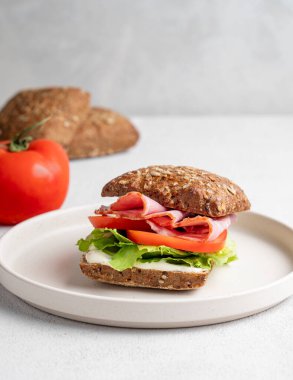 Jambonlu, peynirli, domatesli, salatalı ve soslu tahıllı sandviç. Sağlıklı ve diyet kahvaltı konsepti. Ön görünüm, boşluğu kopyala.