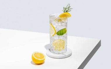 Limonlu limonata, biberiye ve beyaz bir masada buzlu bir bardak. Yaz turunçgil içeceği ya da kafe reklamları için mojito kokteyli konsepti. Ön görünüm ve boşluk kopyala.